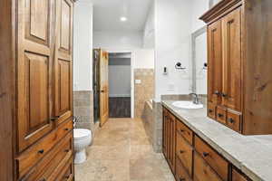 Bathroom featuring tile walls, vanity, wainscoting, and a relaxing tiled tub