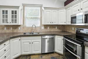 Kitchen featuring stainless steel appliances, backsplash, and white cabinetry