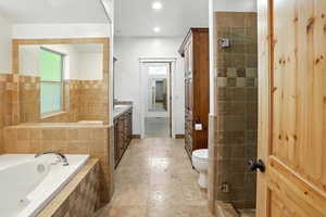 Bathroom with vanity, a bath, recessed lighting, and a tile shower