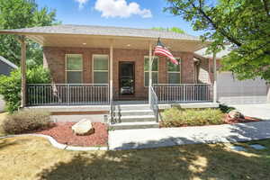 View of front of house featuring covered porch, brick siding, an attached garage, driveway, and a shingled roof