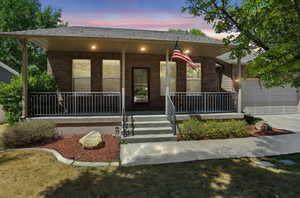 View of front of house featuring covered porch, brick siding, an attached garage, and concrete driveway