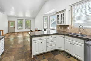 Kitchen with a peninsula, vaulted ceiling, stone tile flooring, healthy amount of natural light, and recessed lighting