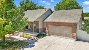 View of front of house featuring an attached garage, a shingled roof, brick siding, and concrete driveway