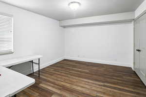 Unfurnished office featuring dark wood finished floors and baseboards