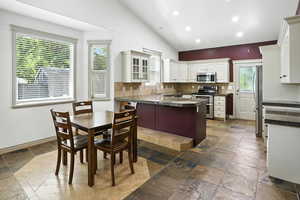 Kitchen featuring stone tile flooring, appliances with stainless steel finishes, healthy amount of natural light, recessed lighting, and backsplash