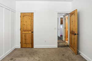 Unfurnished bedroom with carpet flooring and baseboards