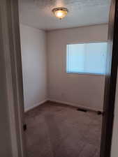 Carpeted spare room featuring baseboards and a textured ceiling