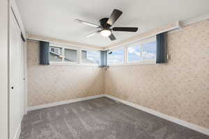Spare room with a textured ceiling, carpet floors, wallpapered walls, and ceiling fan