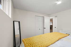 Carpeted bedroom with a textured ceiling and a closet