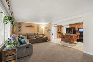 Living area featuring light colored carpet, ornamental molding, light tile patterned floors, and a textured ceiling