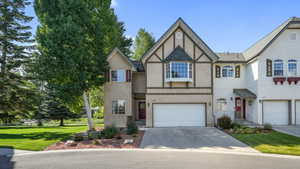 View of front of home featuring driveway, stucco siding, a garage, and a front yard