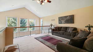 Carpeted family room featuring a ceiling fan and high vaulted ceiling