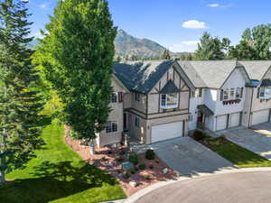 Home with driveway, a garage, stucco siding, a mountain view, and a front yard