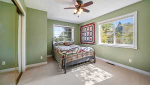 Carpeted bedroom featuring multiple windows, a closet, and a ceiling fan