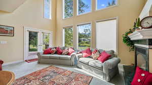 Living area featuring a gas fireplace, carpet, healthy amount of natural light, a towering ceiling, and french doors