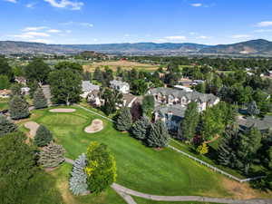 Aerial perspective of suburban area featuring a mountain backdrop and a golf course