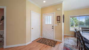Foyer with crown molding, light wood finished floors, and recessed lighting