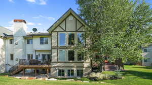 Back of house featuring stairway, stucco siding, a wooden deck, and a yard