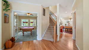 Entry way looking at stairs featuring ornamental molding, wood finished floors, pool table, and ceiling fan