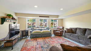 Living area featuring carpet floors, a electric fireplace heater, and recessed lighting