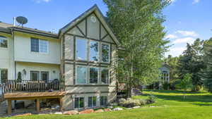 Back of property with stucco siding, a lawn, and a deck