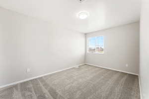 Carpeted empty room featuring baseboards