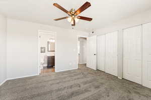 Unfurnished bedroom with carpet flooring, two closets, ensuite bathroom, and a ceiling fan
