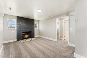 Unfurnished living room featuring a brick fireplace and light carpet