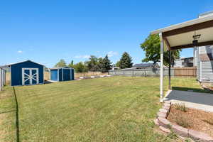 Fenced backyard with a storage unit and a patio area