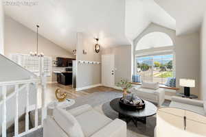 Living room featuring high vaulted ceiling, a chandelier, and light wood-type flooring