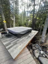 Deck with a covered hot tub and a forest view