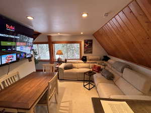 Living room with lofted ceiling, recessed lighting, and light colored carpet