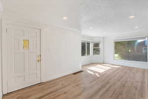 Entrance foyer with ornamental molding, recessed lighting, LVP floors, and a textured ceiling