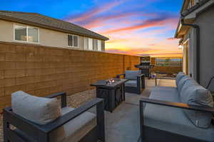 Fenced backyard with a patio area, an outdoor living space with a fire pit, and grilling area