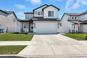 Traditional-style home featuring concrete driveway, an attached garage, roof with shingles, and board and batten siding
