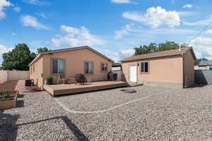 Back of house featuring a wooden deck, fire pit, rock garden and a raised garden beds
