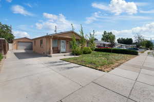 Single story home with stucco siding, driveway, covered porch, and a front yard