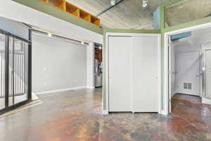 Unfurnished bedroom featuring finished concrete flooring, a closet, access to balcony