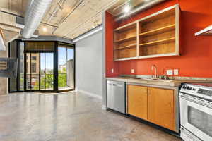 Kitchen with appliances with stainless steel finishes, concrete flooring, open shelves, and light countertops