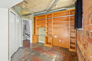 Unfurnished bedroom featuring finished concrete flooring, a closet, and built in storage shelves.