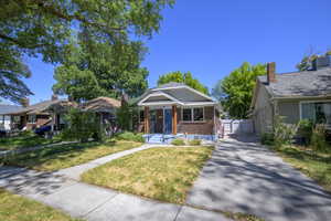 Bungalow featuring a gate, a porch, and brick siding