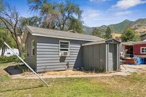 Rear view of property with roof with shingles, a mountain view, a shed, and a lawn
