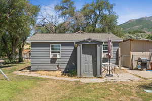 View of front facade with a shingled roof and a shed