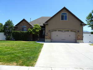 View of front facade with stone siding, concrete driveway, and stucco siding. Faces West.
