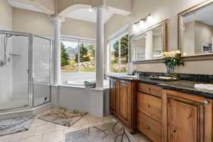 Full bath featuring ornate columns, a bath, double vanity, a shower stall, and tile patterned floors