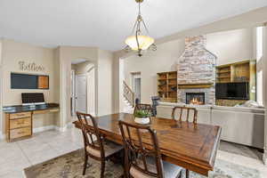 Dining space featuring arched walkways, a fireplace, stairway, and light tile patterned floors