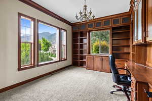 Unfurnished office featuring a chandelier, carpet floors, a mountain view, ornamental molding, and built in features