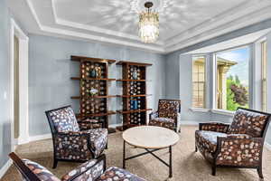 Living area with carpet floors, a raised ceiling, and a chandelier