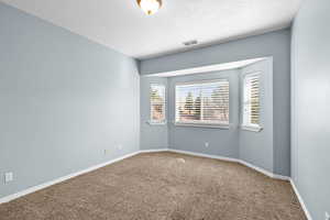 Spare room featuring carpet floors and a textured ceiling