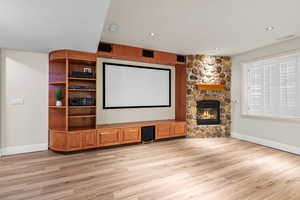 Home theater room featuring light wood-style floors, a stone fireplace, and recessed lighting